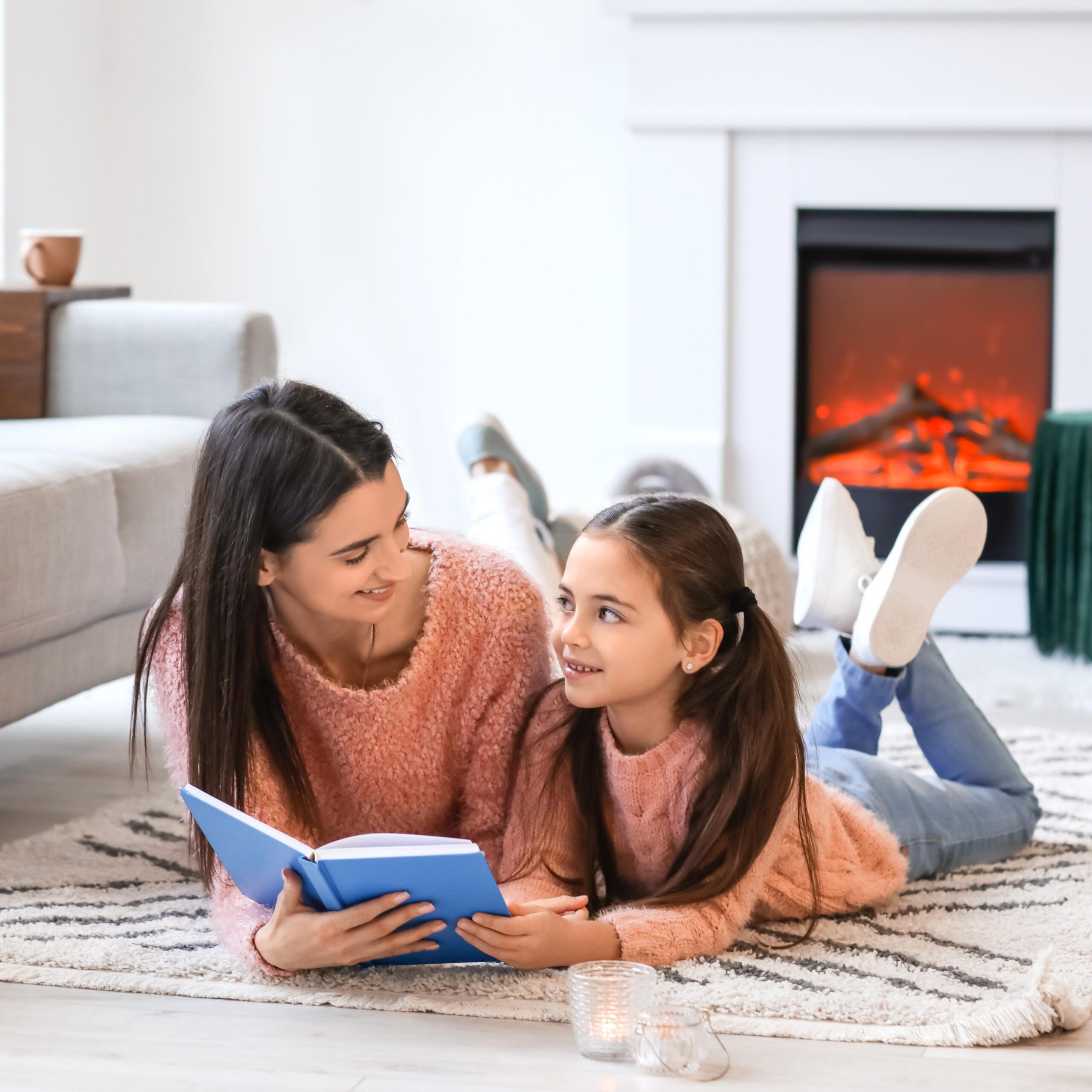 Mom and Daughter reading book in front of fireplace